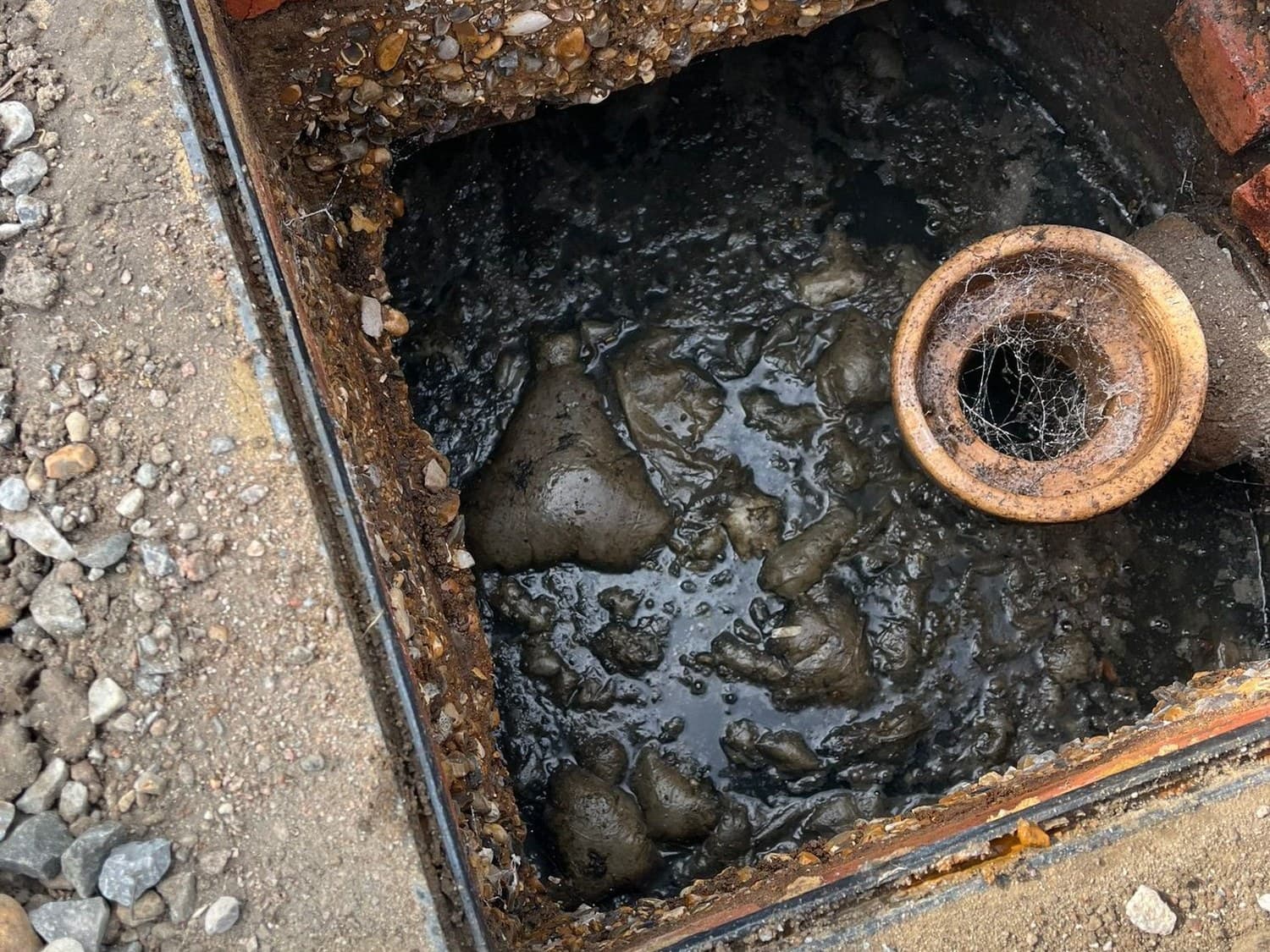 Brick built inspection chamber opened up showing the clay inlet pipe and standing waste