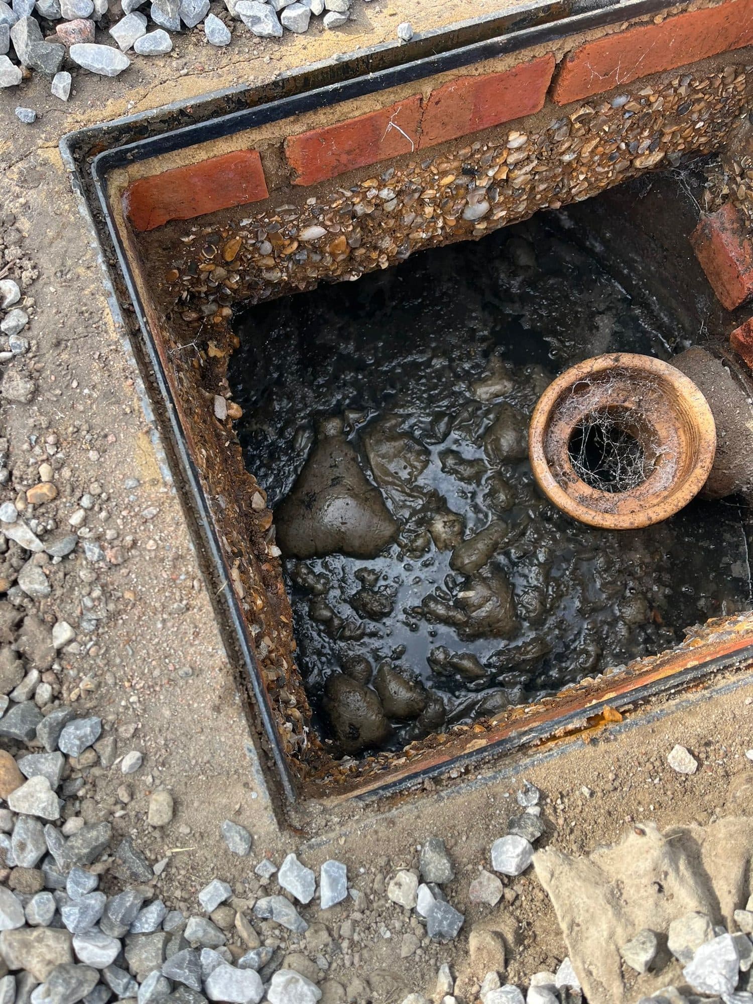 Brick built inspection chamber opened up showing the clay inlet pipe and standing waste