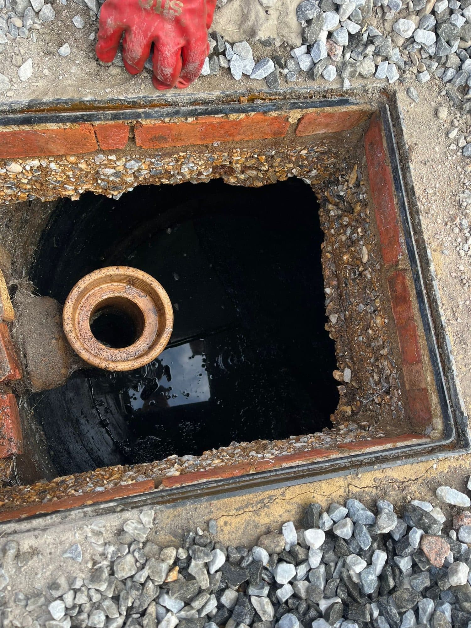 Engineer inspecting a brick chamber and clay pipe after clearing a blockage