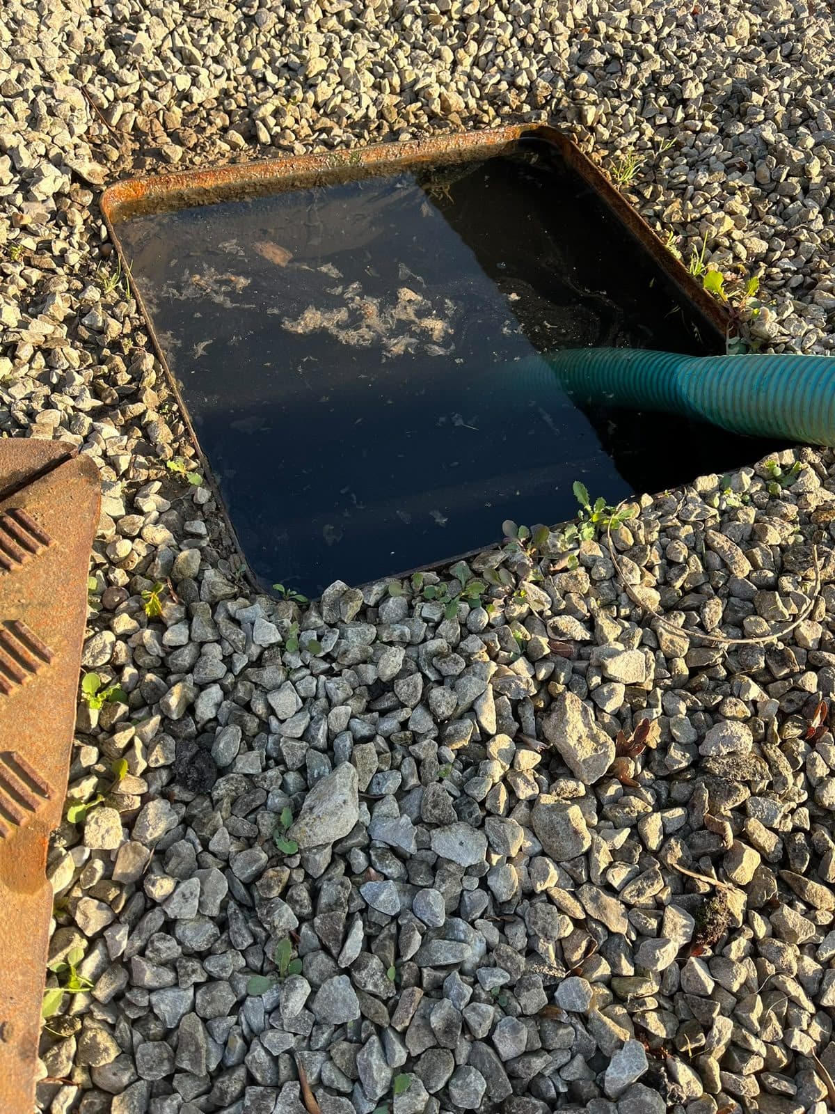 Rectangular chamber set in a gravel bed being emptied through the suction hose