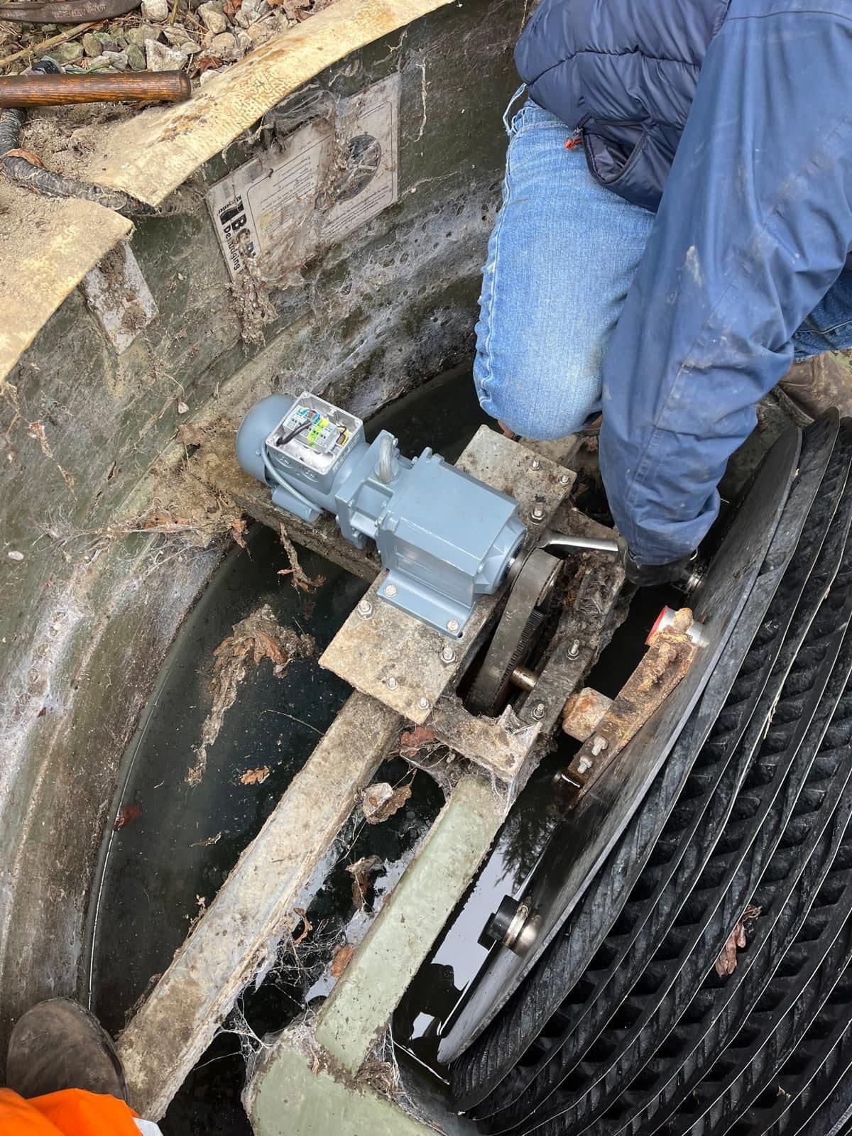 Engineer reaching into a sewage treatment plant to fit the drive motor and gearbox