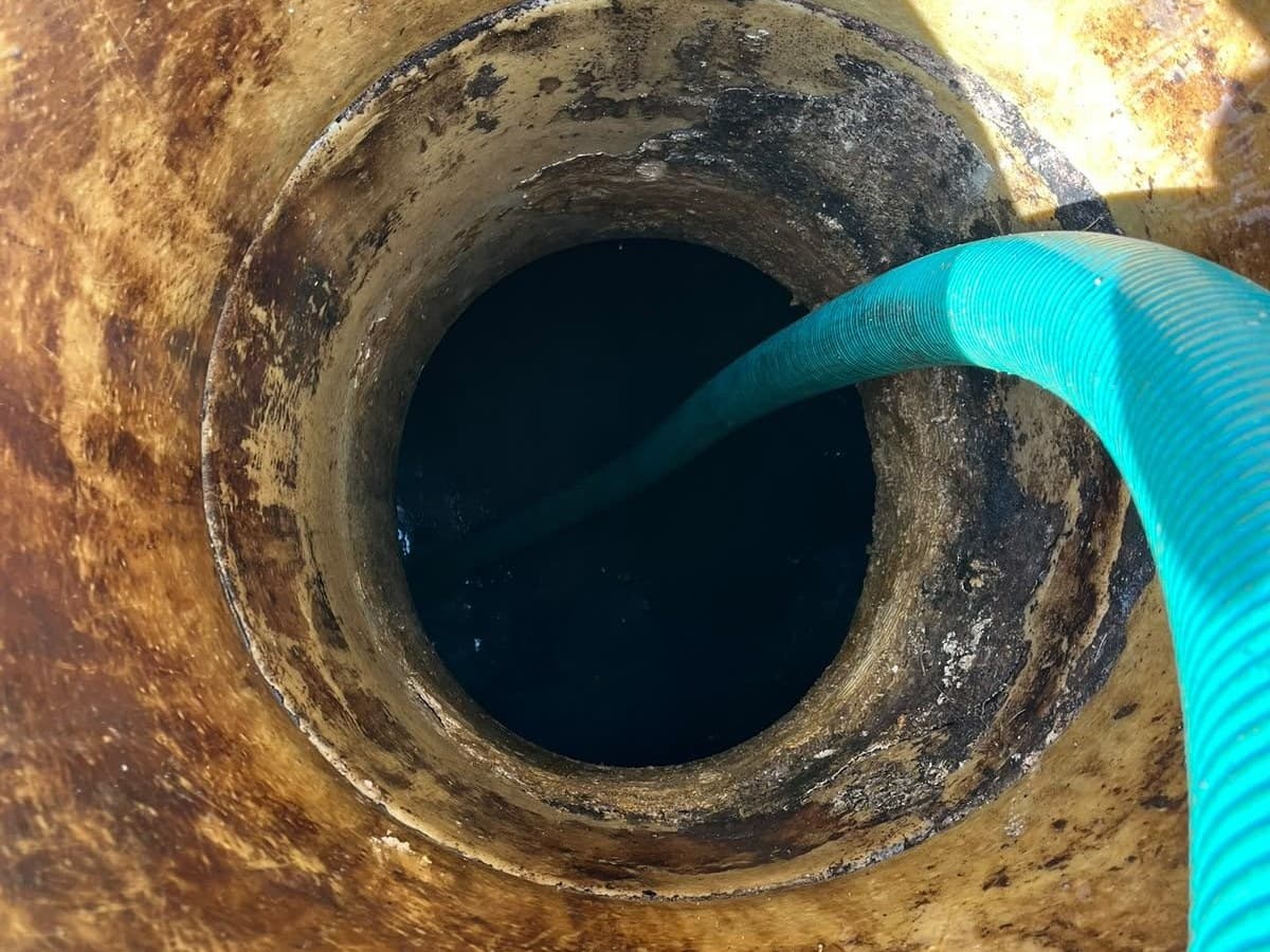 Suction hose lowered down into a round underground tank through its access opening
