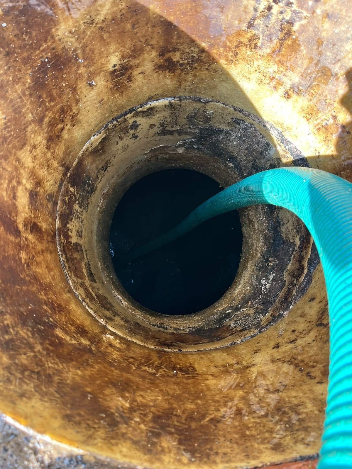 Suction hose lowered down into a round underground tank through its access opening