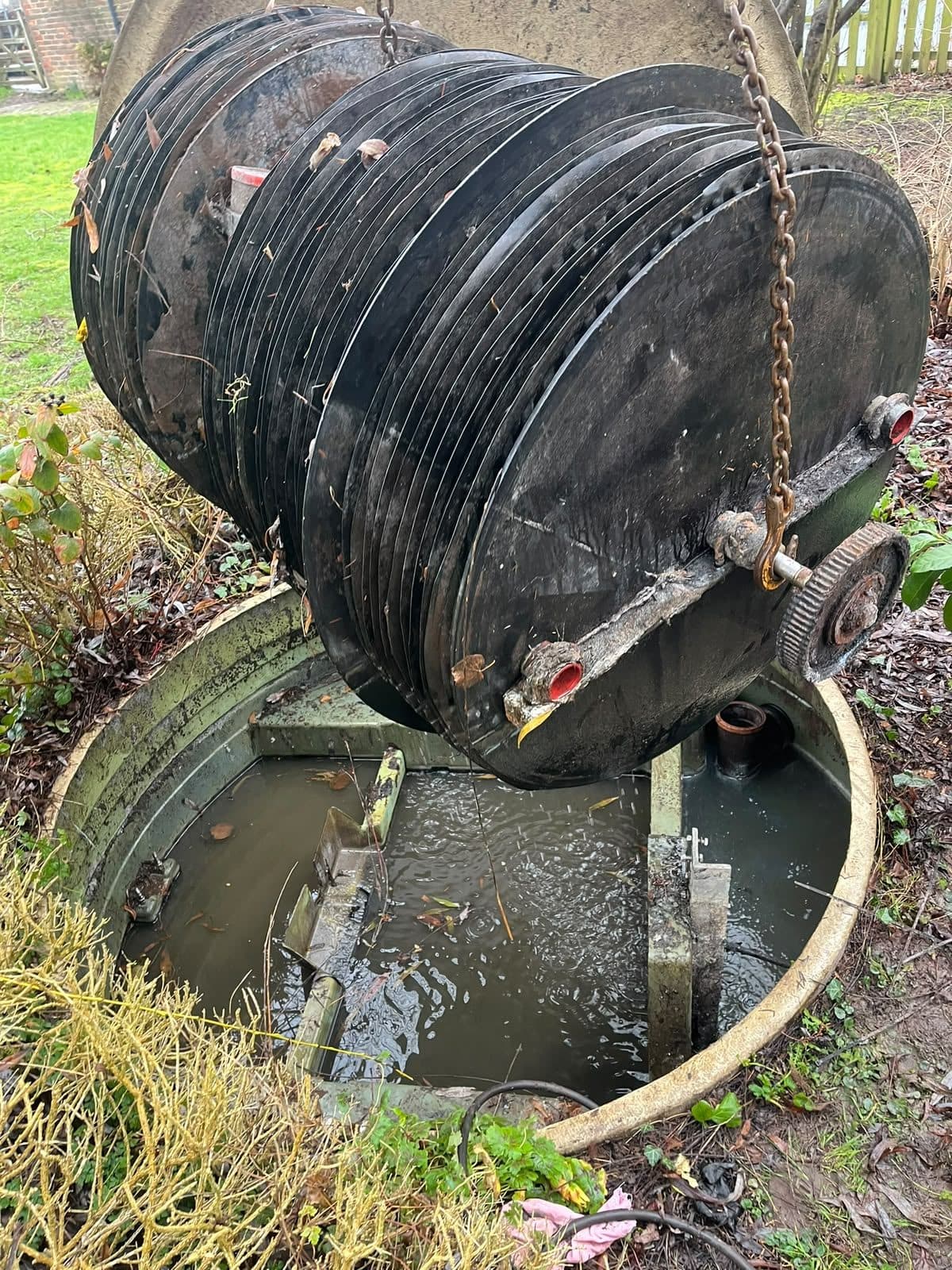 Treatment plant unit lifted out of its chamber on chains for servicing