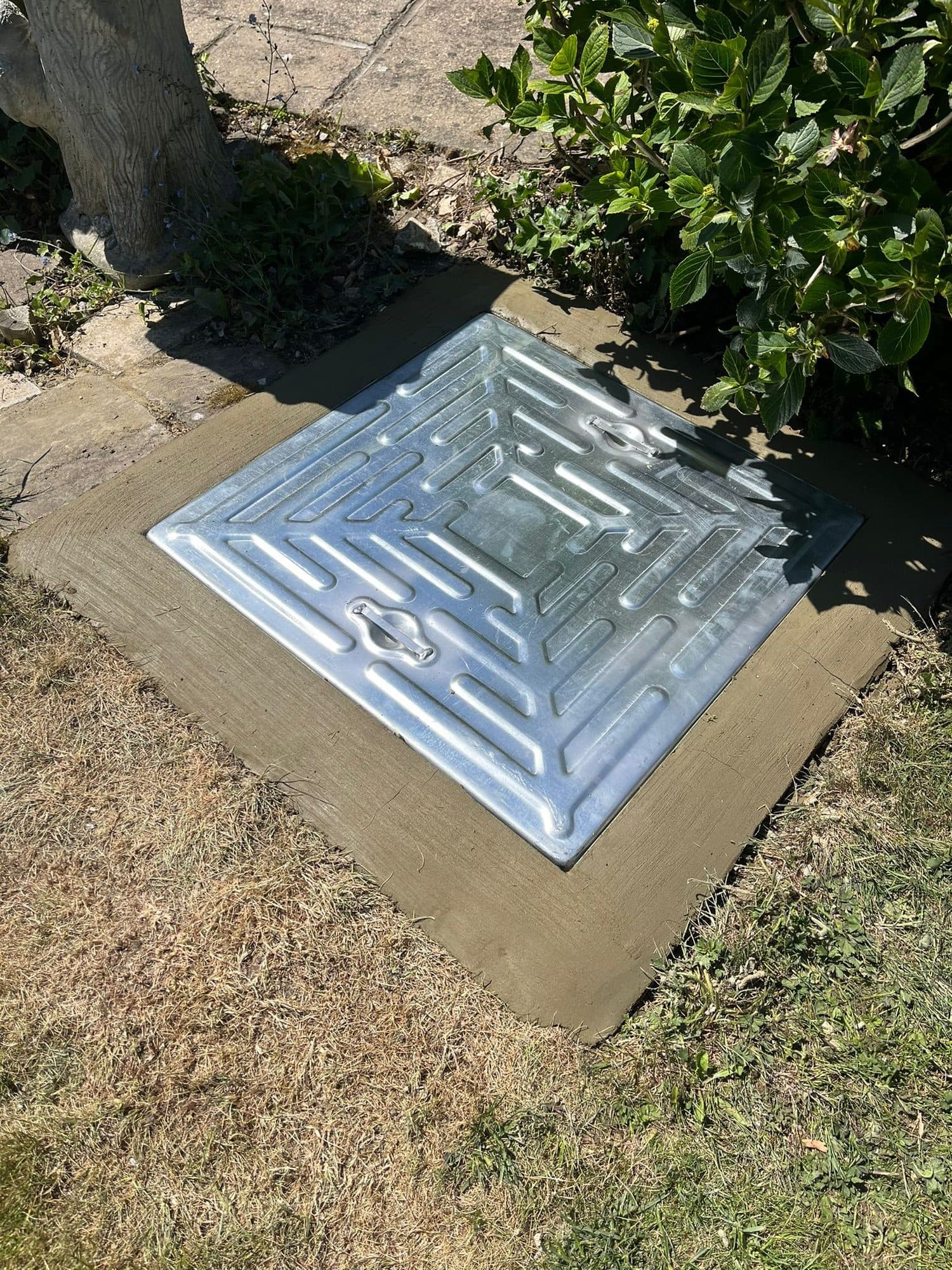 New galvanised steel chamber cover bedded into fresh concrete after an installation