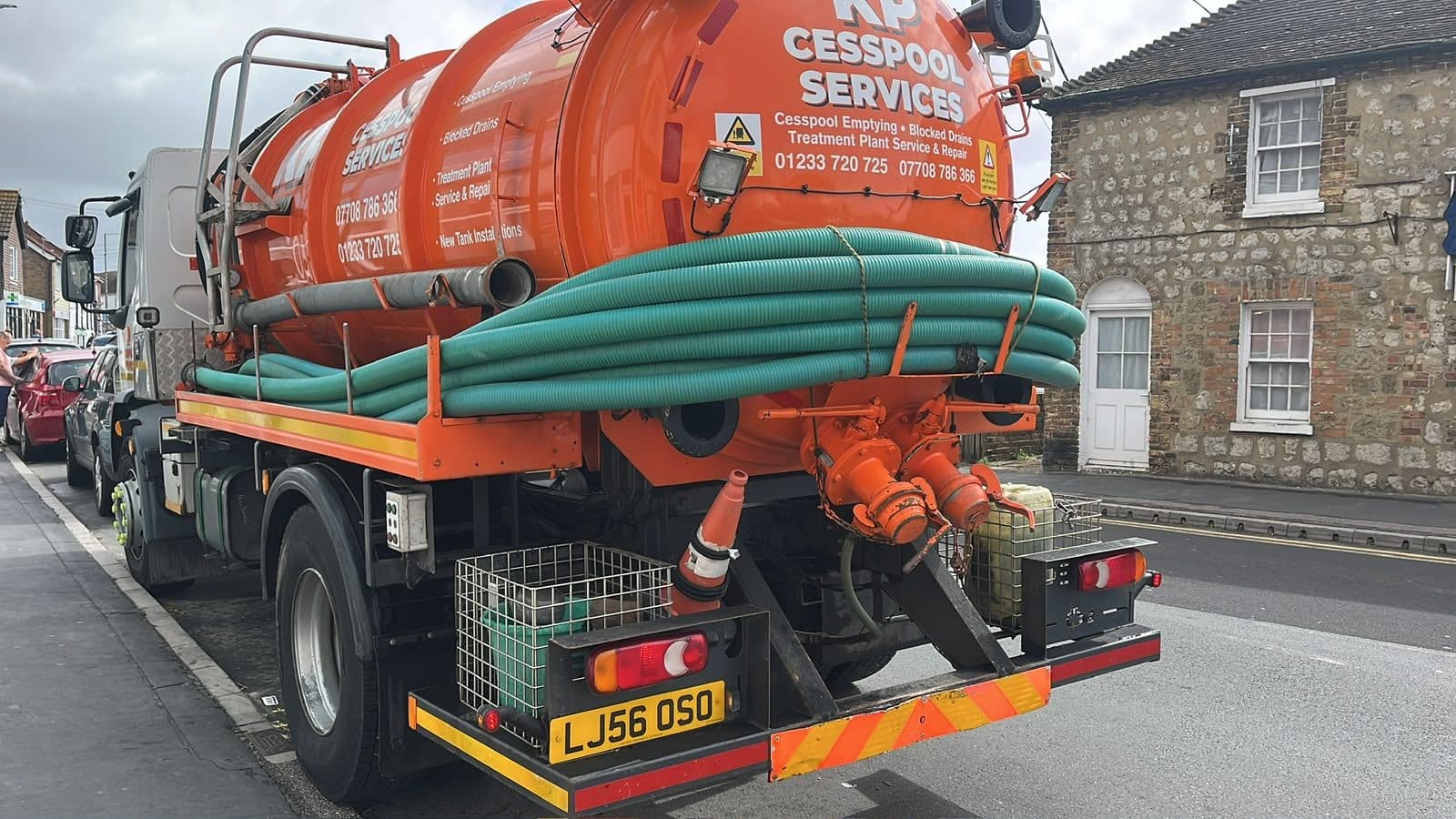 KP Cesspool Services tanker working kerbside on a village street with its hose coiled